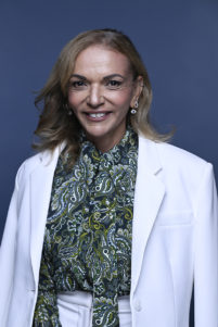 The Hon Dr Anne Aly sits for a portrait on a blue background